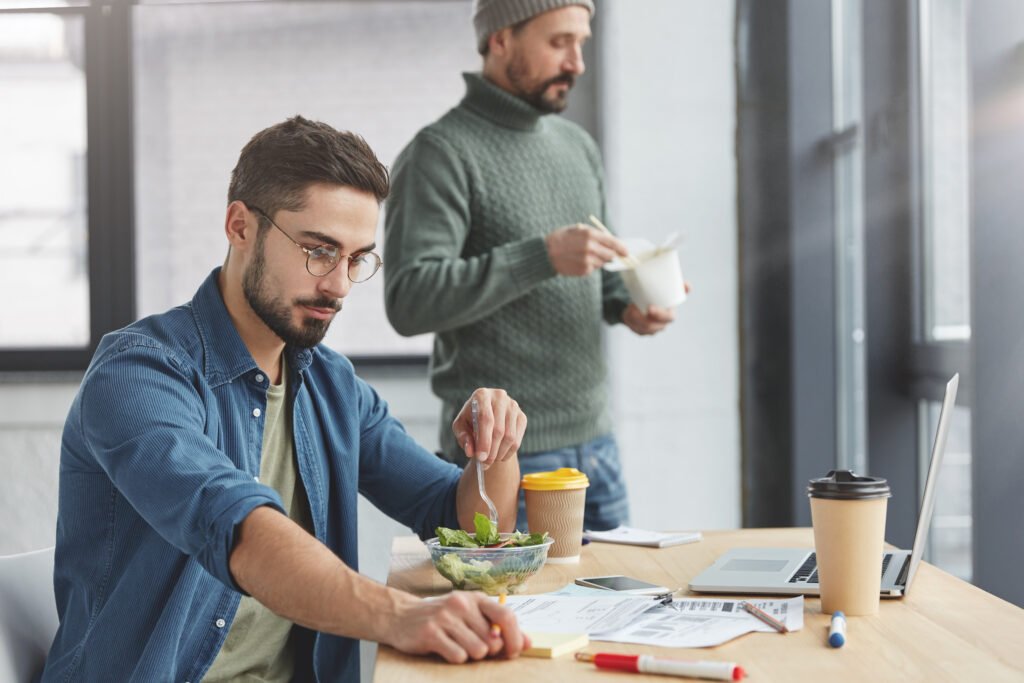 The current image has no alternative text. The file name is: coworkers-having-lunch-office-scaled.jpg